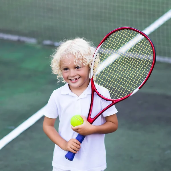 Ребенок, играя в теннис на открытом корте — стоковое фото